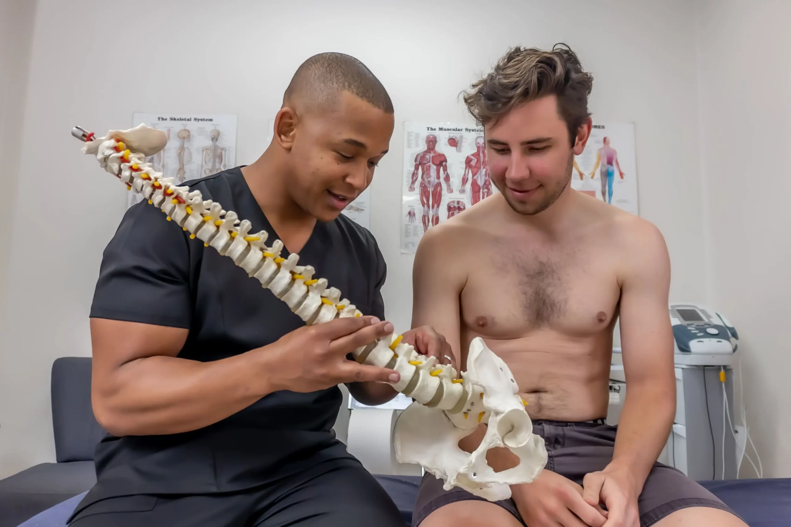 Floyd Lebatie explaining spinal anatomy using model to educate patient on post-surgical recovery